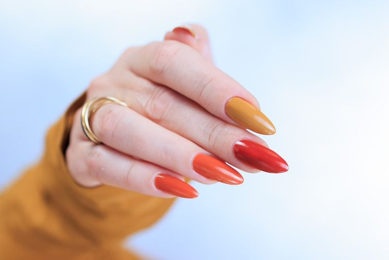 mano de mujer con uñas largas naranjas 