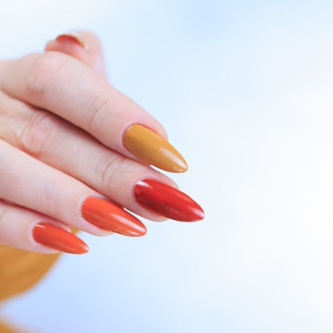 mano de mujer con uñas largas naranjas 